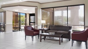 Un vestíbulo amplio con un sofá grande, dos sillones y una mesa de centro. Se ve una ventana grande con vistas al exterior.