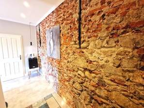 A room with a brick wall, a white door, and a small table with a lamp. - Gutshaus beim Zeilinger Schlössl (Knittelfeld)