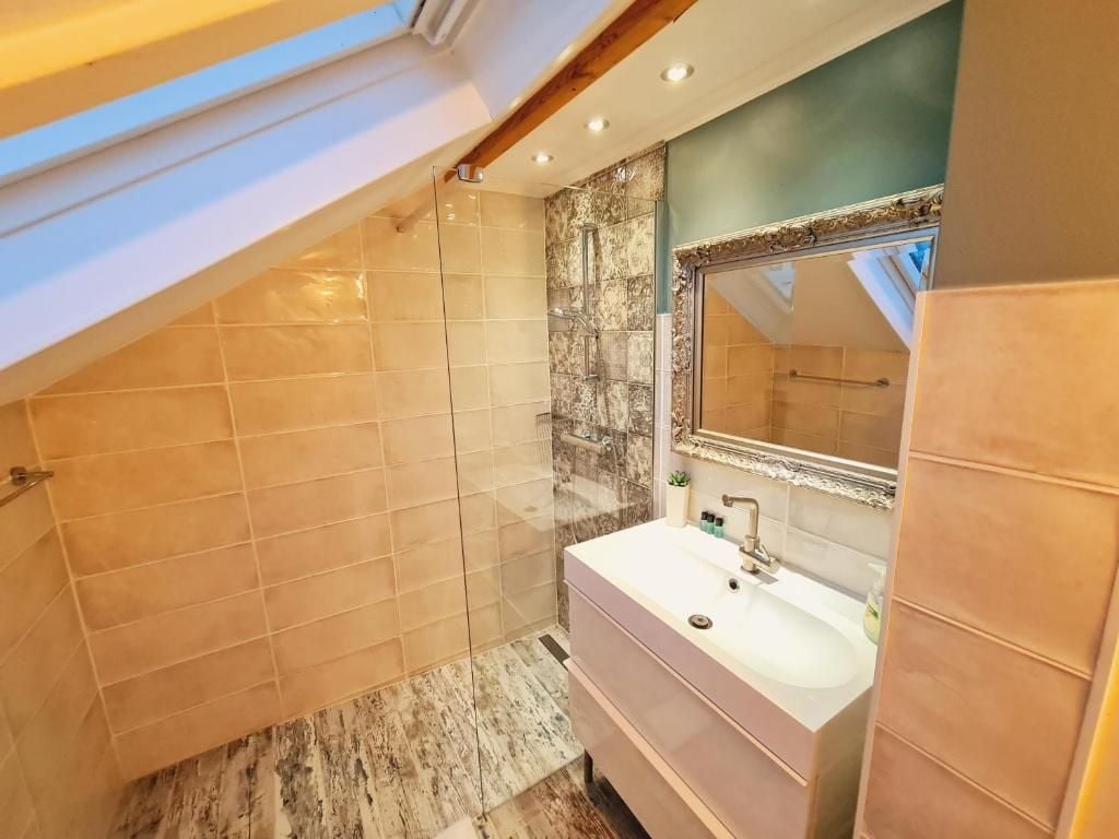 A bathroom with a skylight, a large mirror, and a vanity with a sink.