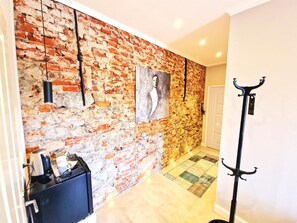 A hallway with a brick wall, a coat rack, and a door. - Gutshaus beim Zeilinger Schlössl (Knittelfeld)