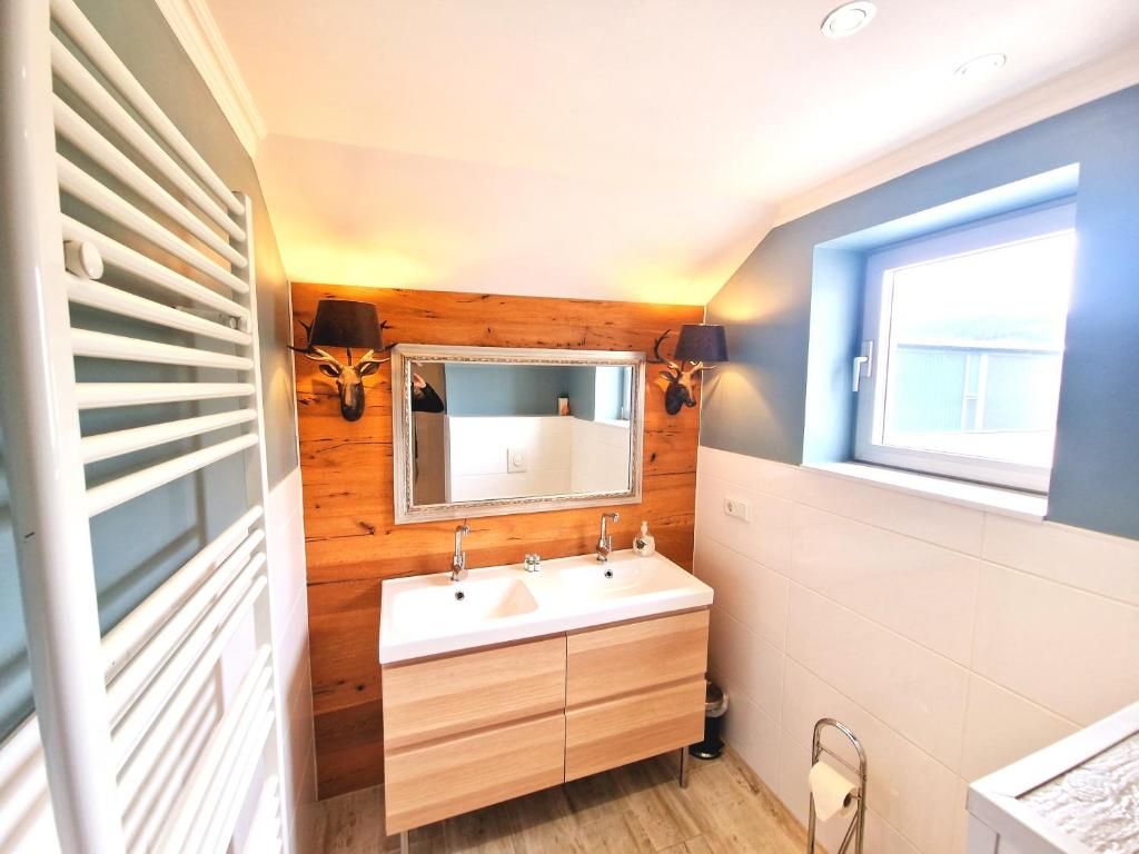 Une salle de bain avec un meuble-lavabo en bois, un miroir et une fenêtre.