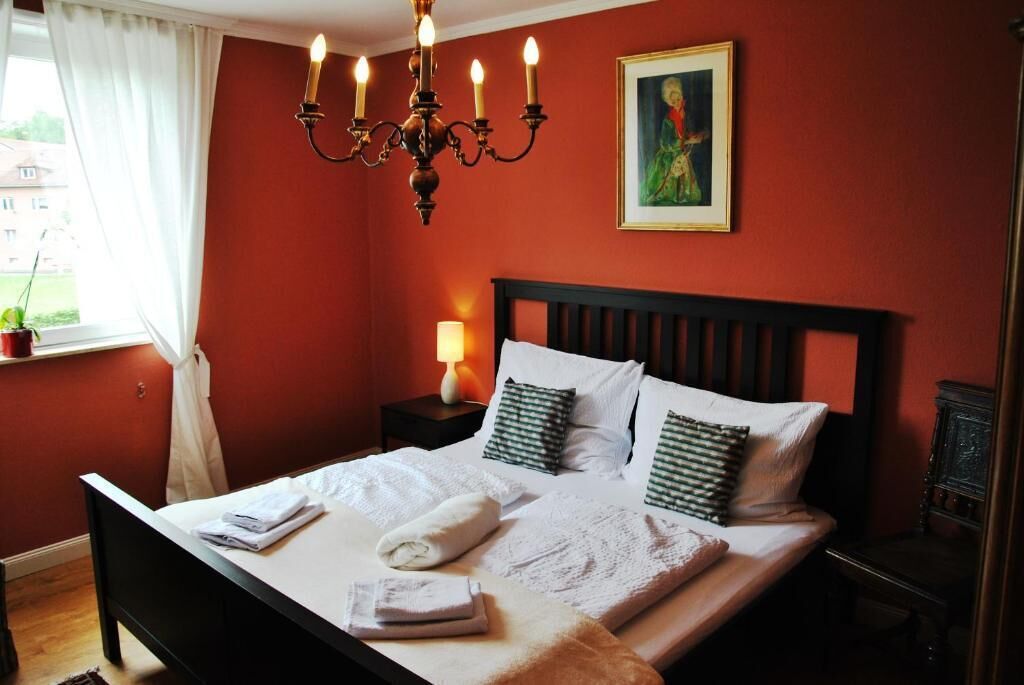 Een hotelkamer met een bed, een nachtkastje, een lamp en een schilderij aan de muur.