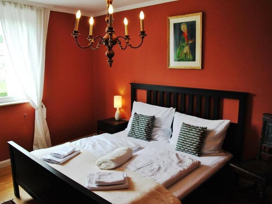 Een hotelkamer met een bed, een nachtkastje, een lamp en een schilderij aan de muur.