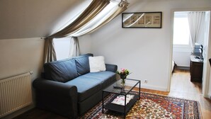 A living room with a dark blue sofa, a glass coffee table, and a patterned rug. - Gutshaus beim Zeilinger Schlössl (Knittelfeld)