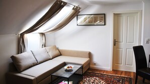 A living room with a sofa, a coffee table, a chair, a patterned rug, and a door. - Gutshaus beim Zeilinger Schlössl (Knittelfeld)