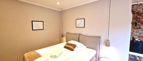 A modern bedroom with a large bed, two bedside tables, and a hanging light fixture.