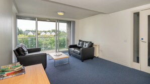 A modern living room with a large window, a leather sofa, a coffee table, and a bookshelf. - Victoria Mills (Cork)