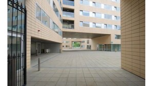 A spacious courtyard with a modern building featuring multiple floors and large windows. - Victoria Mills (Cork)