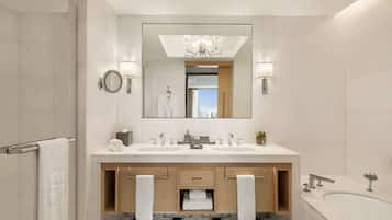 Un baño moderno con un espejo grande, dos lavamanos, una bañera y un perchero para toallas.