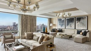 A spacious living room with a large window offering a city view, a chandelier, and a sofa set. - Shangri-La The Fort, Manila (Taguig)