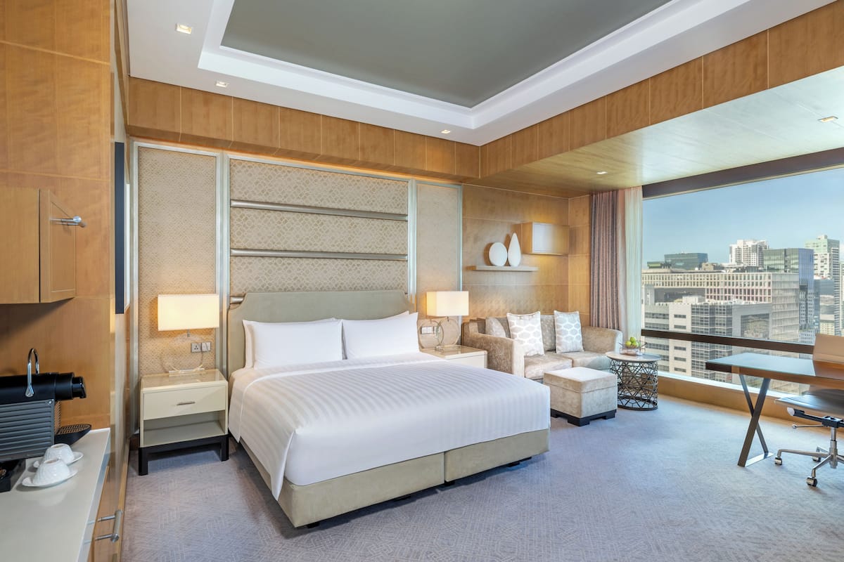 Une chambre d’hôtel moderne avec un grand lit, un canapé, un bureau et une vue sur la ville.