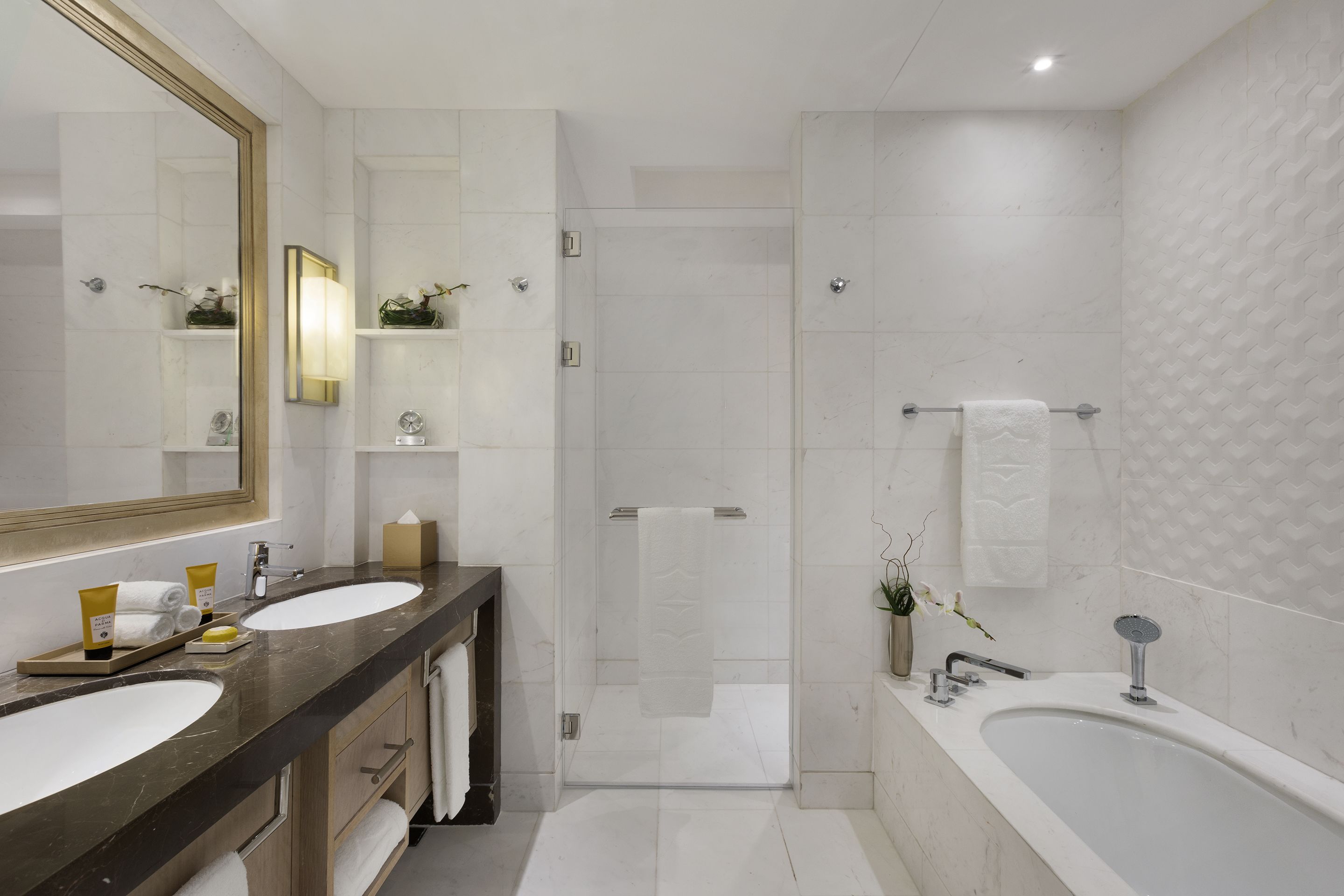 A modern bathroom with two sinks, a large mirror, a shower, and a bathtub.