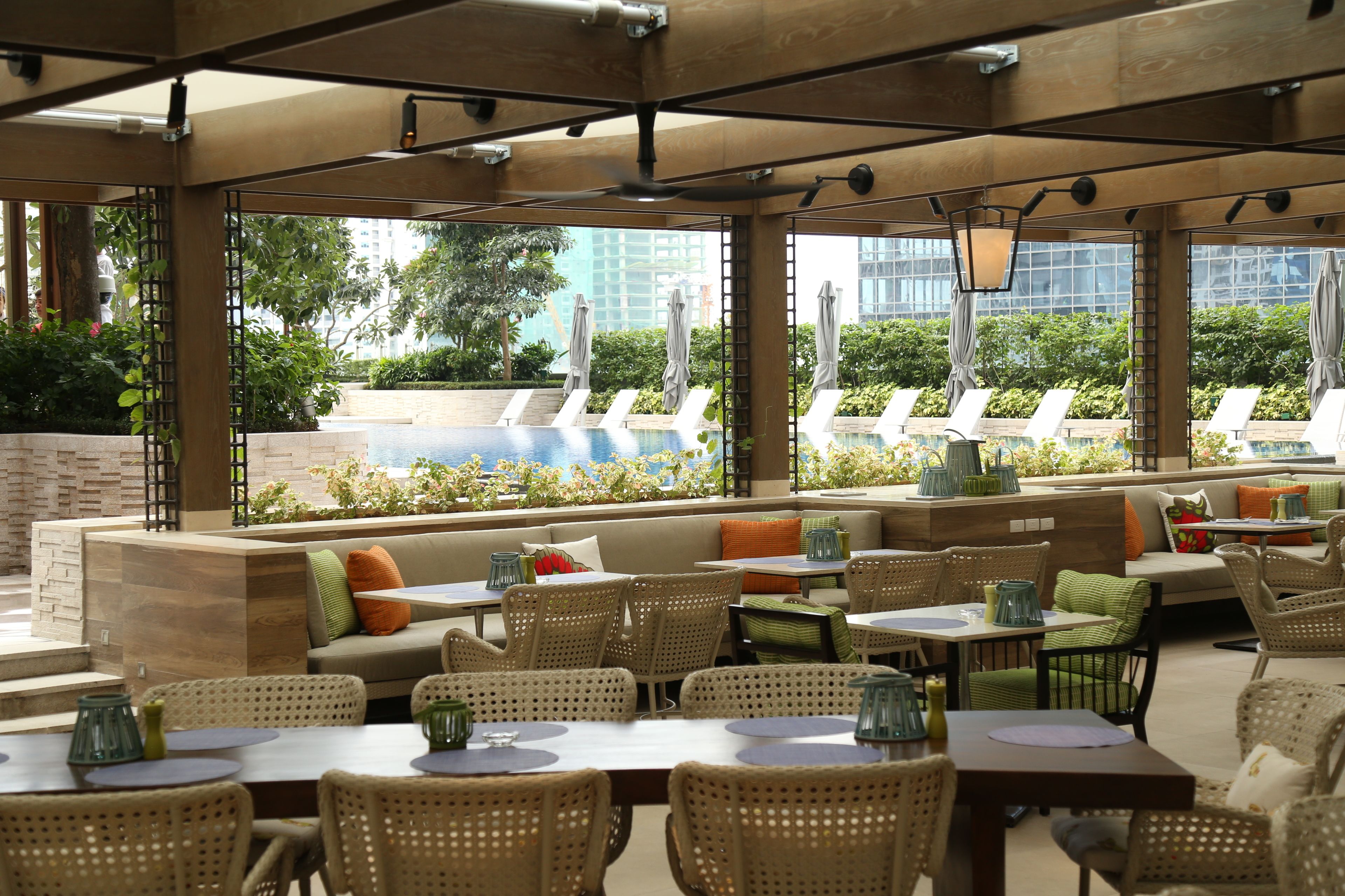 An outdoor dining area with wicker furniture, a pool view, and a modern architectural design.