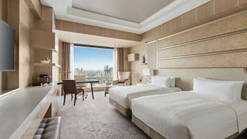 A modern hotel room with a large bed, a desk, a chair, and a view of the city.
