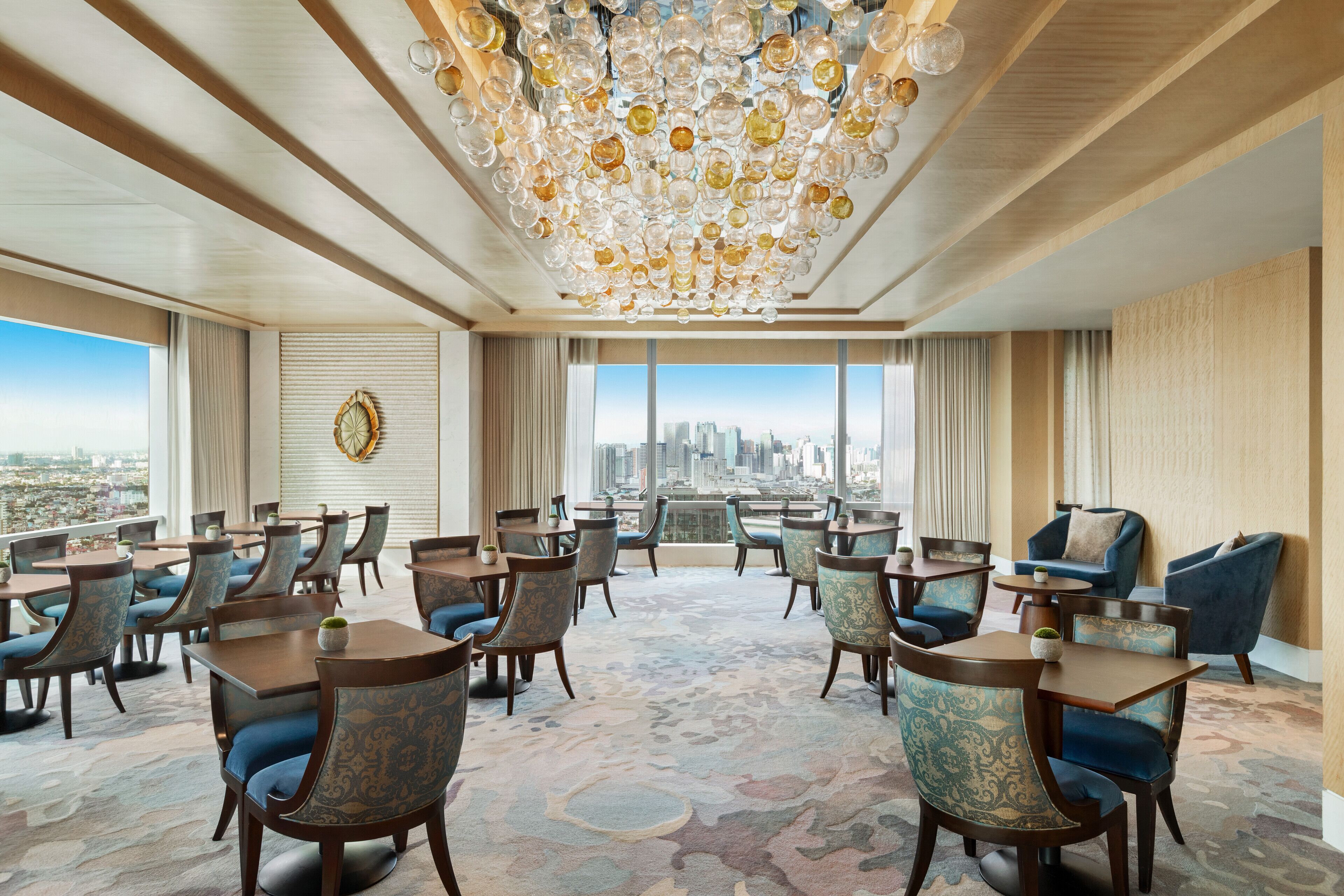 A spacious conference room with a city view, large windows, and a chandelier.
