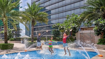Guests can unwind amidst lush greenery and palm trees surrounding a serene water feature with multiple jets.