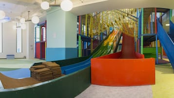 A play area with slides, a climbing net, and a staircase.
