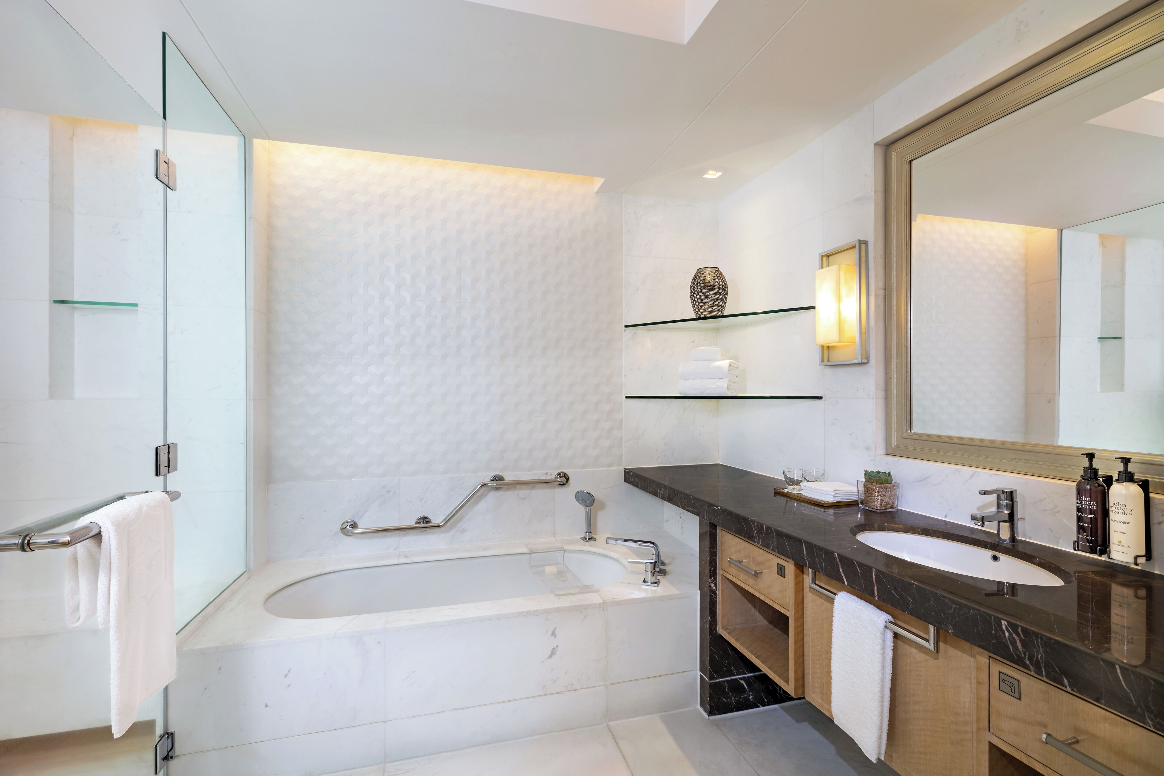 A modern bathroom with a bathtub, a large mirror, and a vanity with a sink.