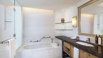 A modern bathroom with a bathtub, a large mirror, and a vanity with a sink.