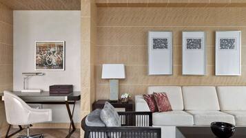 A modern room with a glass desk, a white sofa, and three framed artworks on the wall.