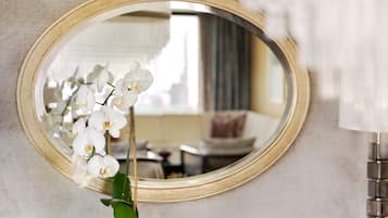 A mirror with a gold frame reflecting an orchid and a room interior.
