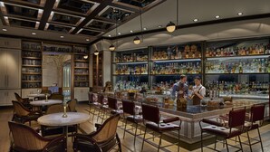 A bar area with a bartender, bookshelves, and a variety of bottles. - Shangri-La The Fort, Manila (Taguig)