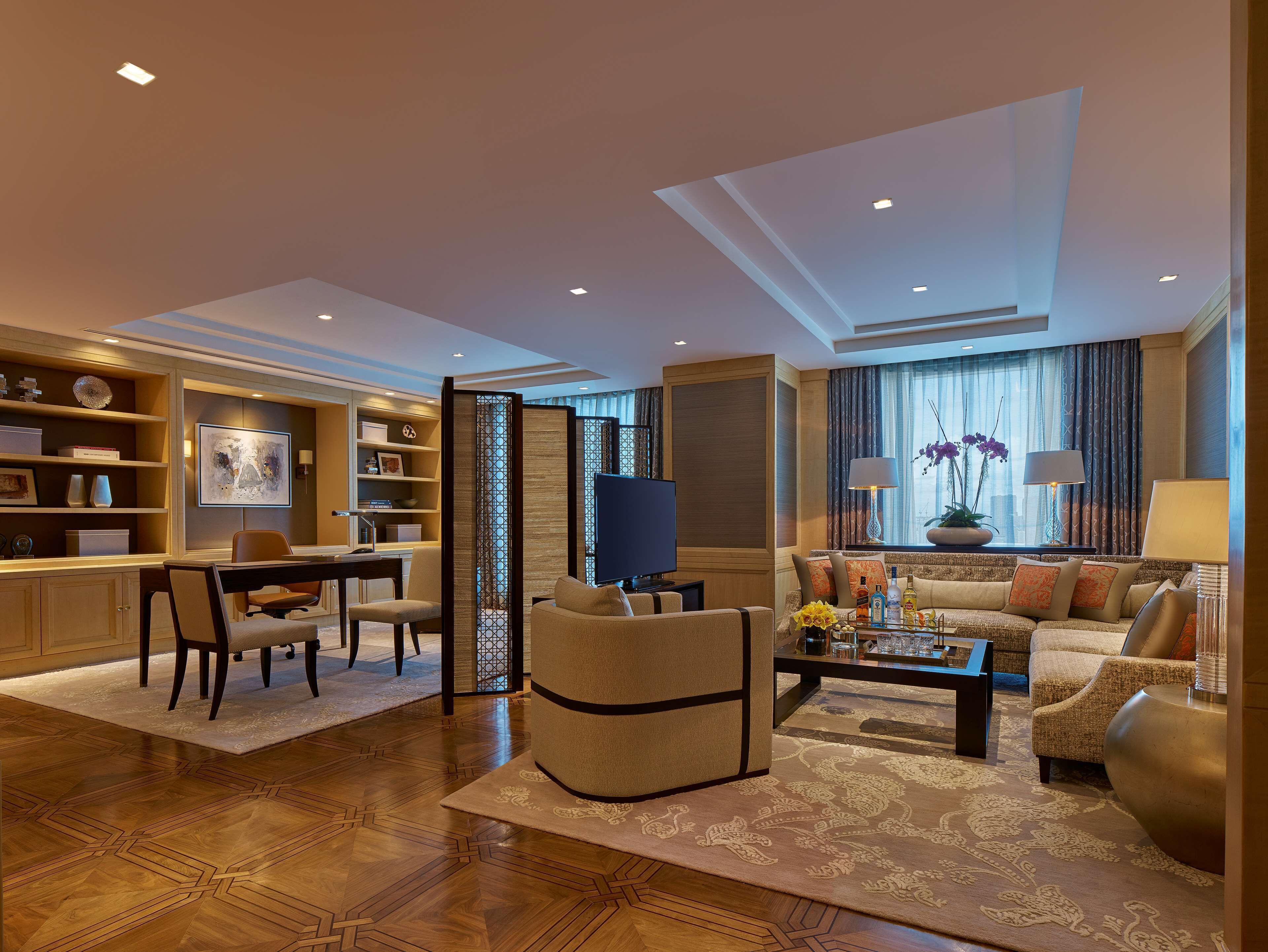 Un salón espacioso con sofá, mesa de centro y televisor. Cuenta con una zona de comedor con mesa y sillas. El suelo es de madera y hay una alfombra decorativa.