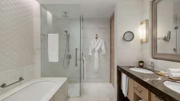 A modern bathroom with a glass-enclosed shower, a large bathtub, and a vanity with two sinks.