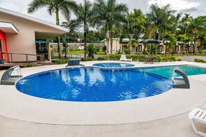 Una amplia piscina al aire libre con sillas de descanso y una fuente.