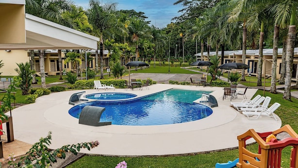 A pool area with lounge chairs and a children's play structure.