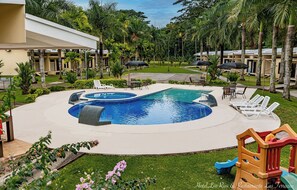 Zona de piscina con sillas de descanso y un parque infantil.