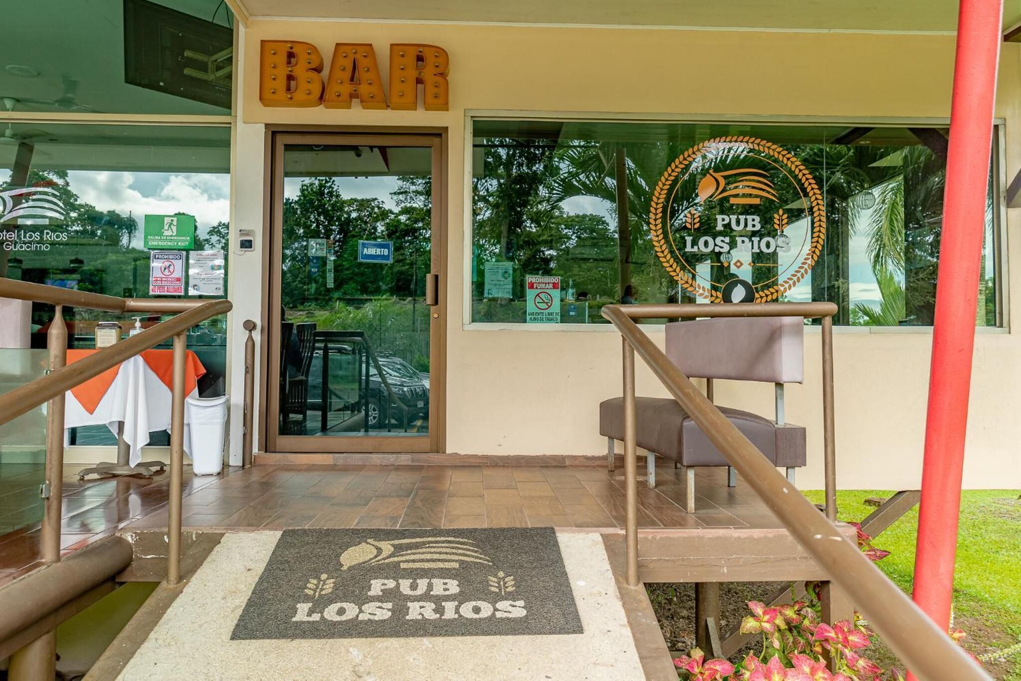 A bar entrance with a doormat, a sign above the door, and a window with a logo.
