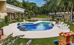Zona de piscina con sillas de descanso y un parque infantil.