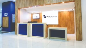 Un área de recepción con paneles de madera, una pantalla grande y un mostrador de recepción.