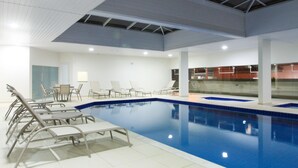 Una piscina interior con sillas de descanso y una mesa.