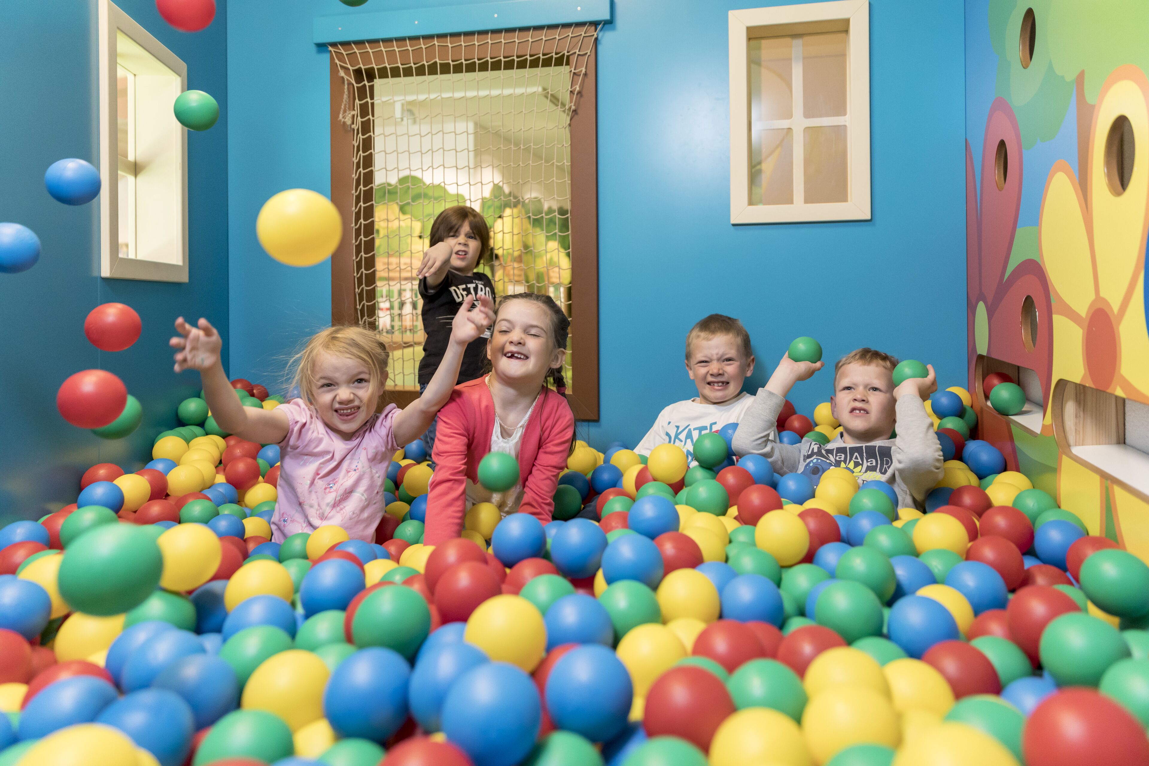 Zona de juegos con pelotas de colores y una entrada con red.