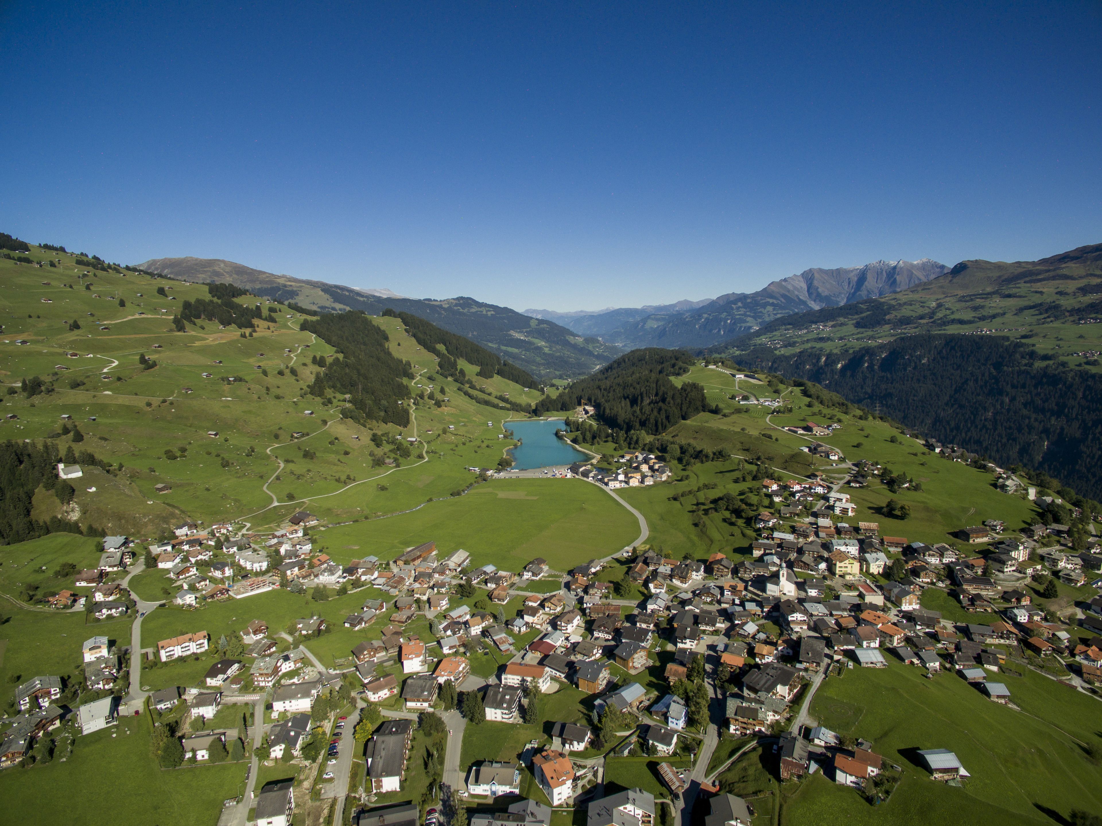 A small town with a lake surrounded by mountains.