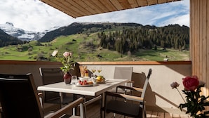 A dining area with a table set for two, a vase with flowers, and a scenic mountain view. - Pradas Resort Brigels (Brigels)