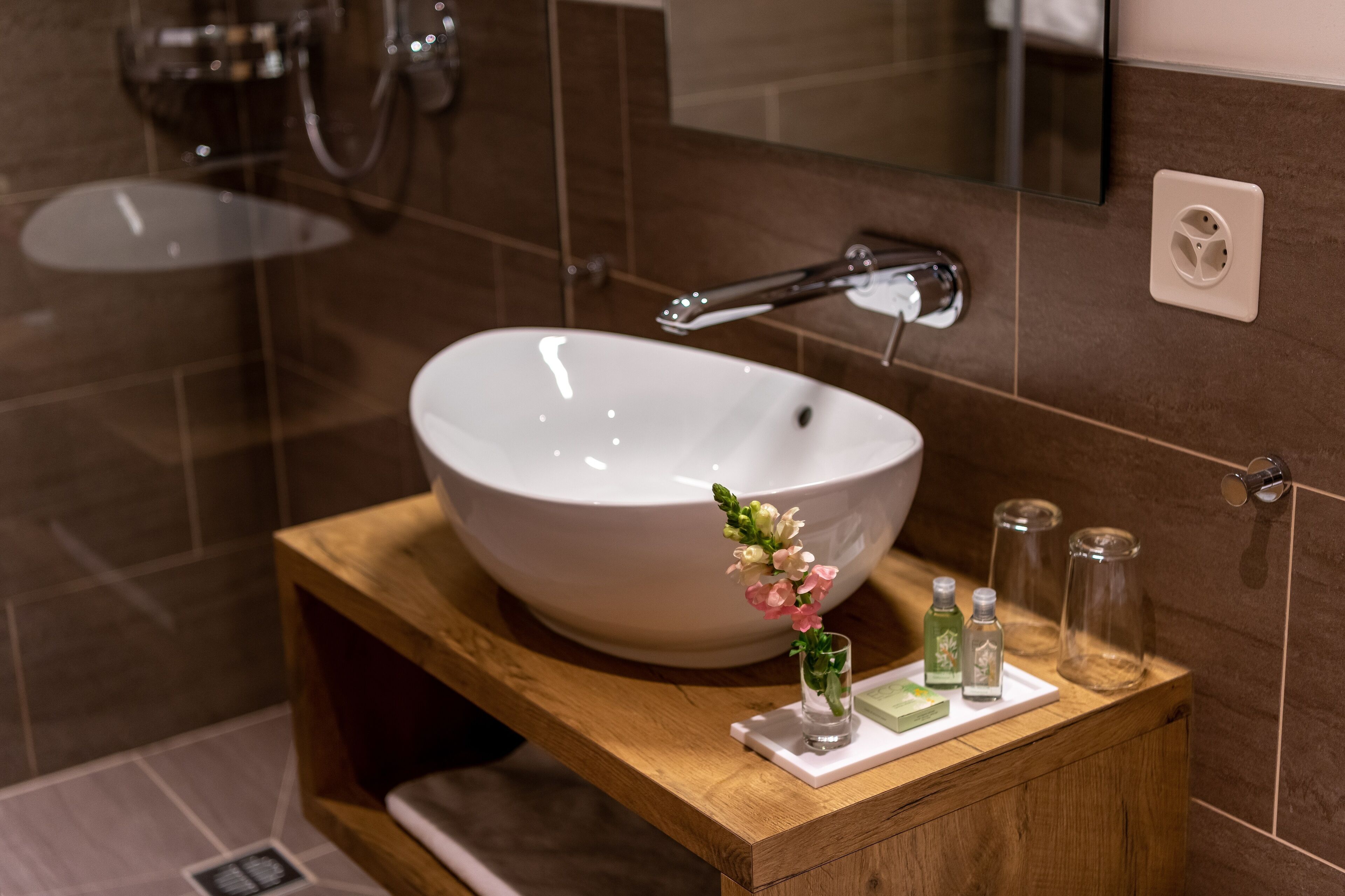 A bathroom with a large white sink, a wooden vanity, and a mirror.