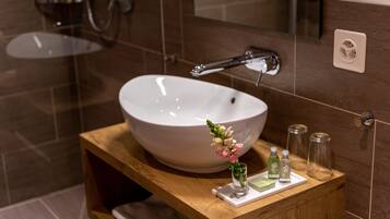 A bathroom with a large white sink, a wooden vanity, and a mirror.