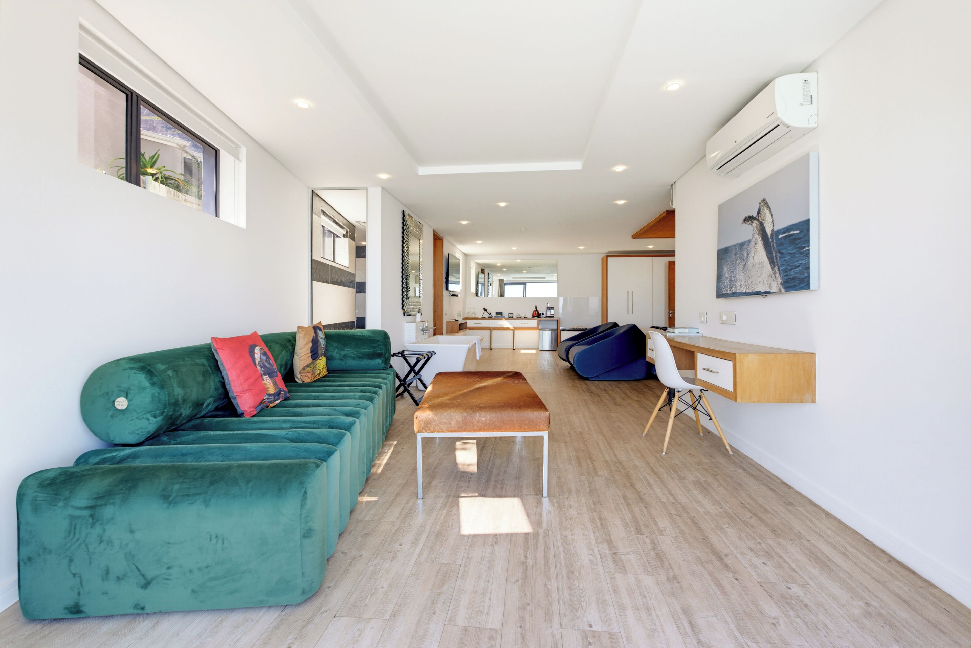 A modern living room with a green sofa, a wooden bench, and a desk with a chair.