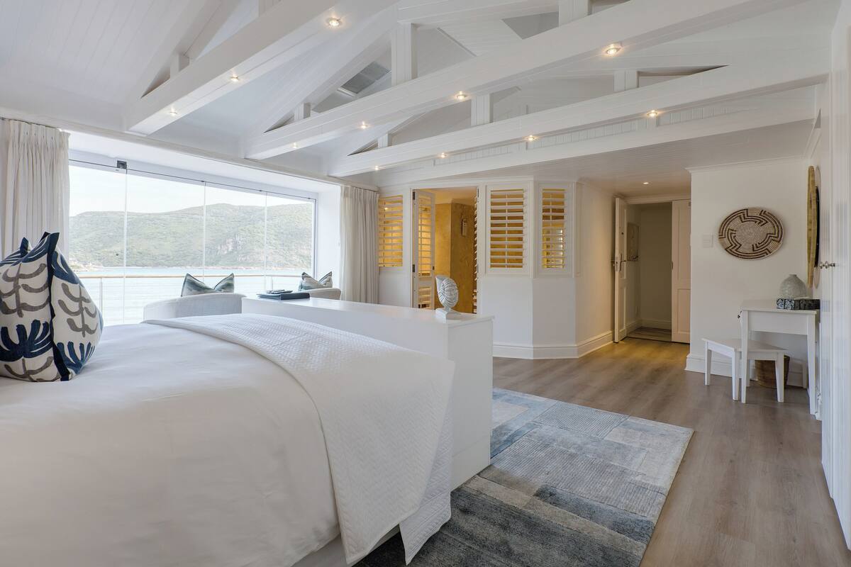 A spacious bedroom with a large bed, a desk, and a view of the outdoors.