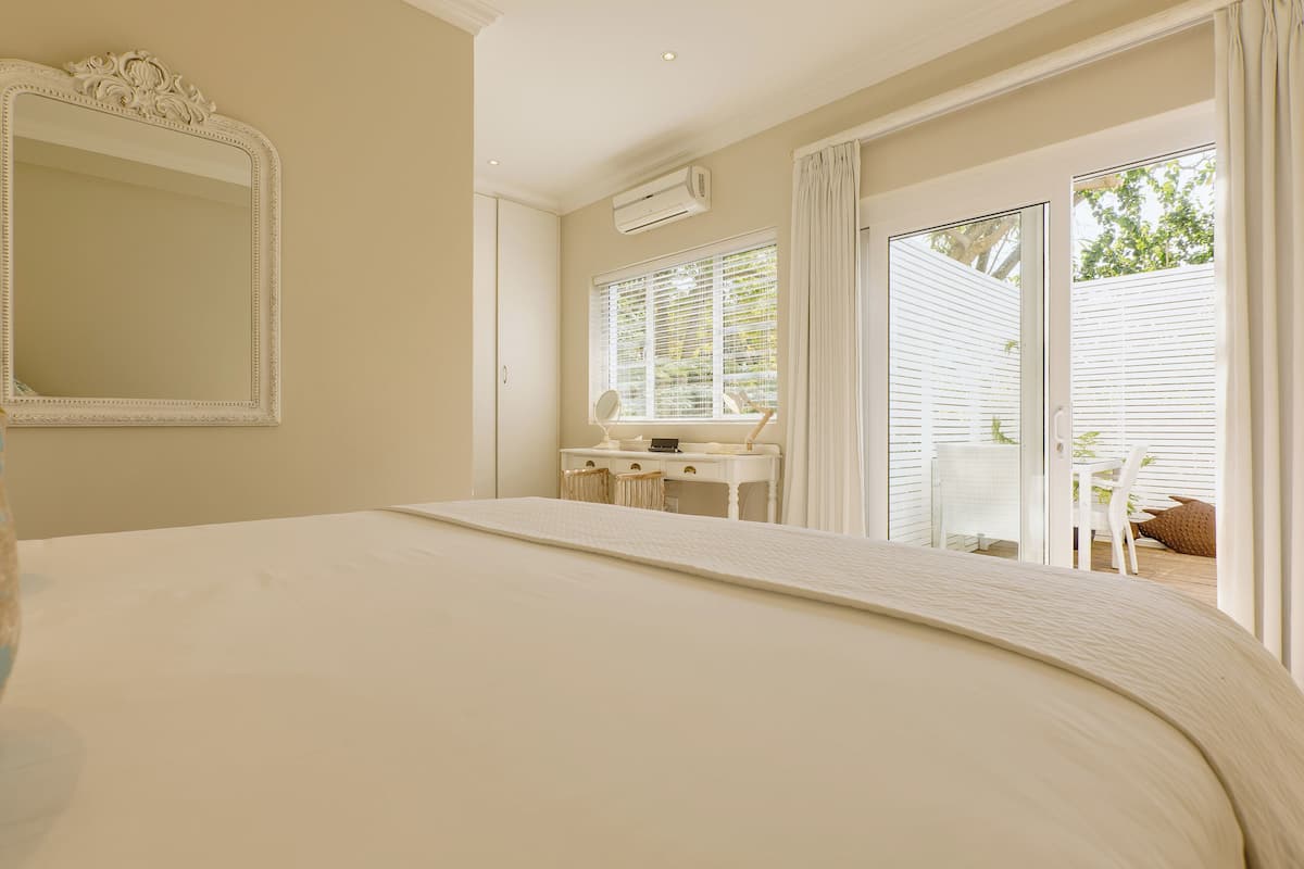 A bedroom with a large bed, a desk with a chair, and a sliding glass door leading to an outdoor area.