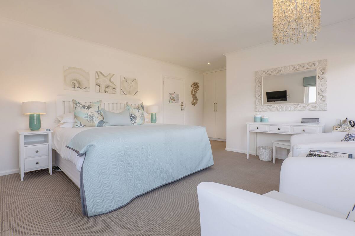 A bedroom with a bed, nightstand, dresser, and a large mirror.