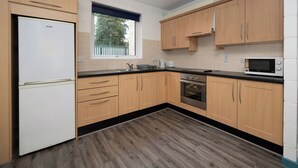 Een moderne keuken met houten kastjes, een ingebouwde oven en een raam voor natuurlijk licht.