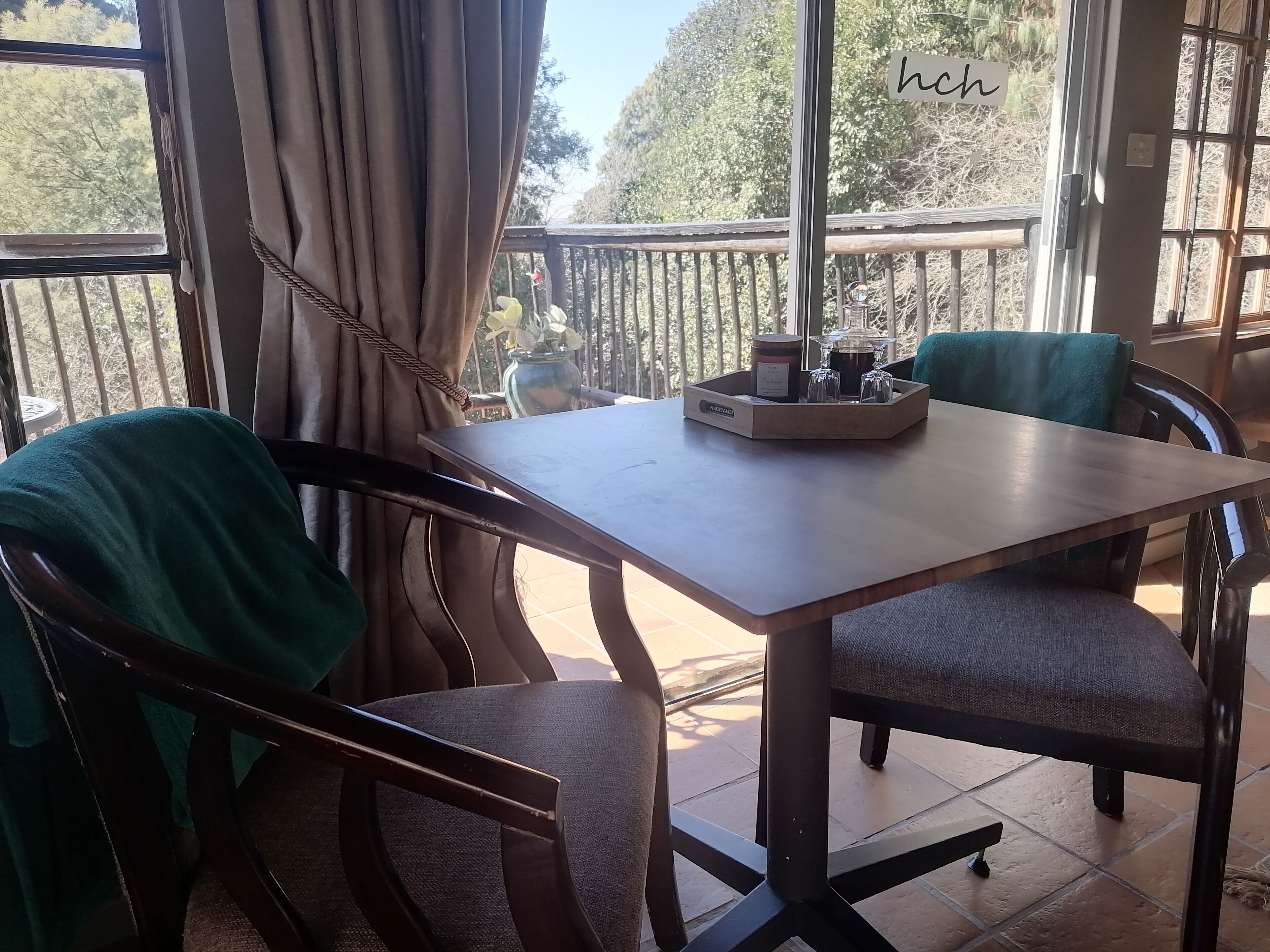 A dining area with a table and chairs, a vase with flowers, and a tray with condiments.