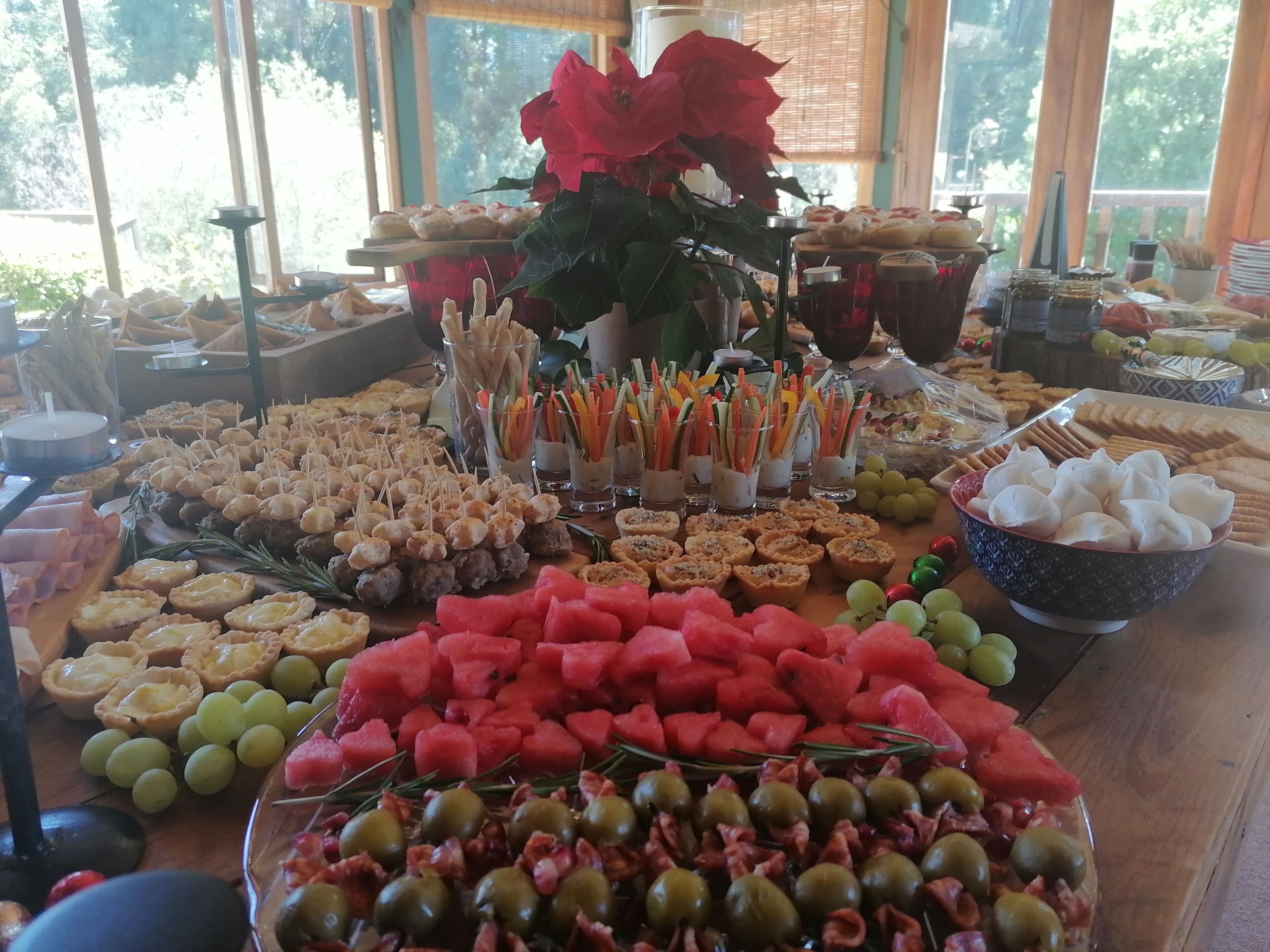 A buffet table with various food items including watermelon, olives, and appetizers.