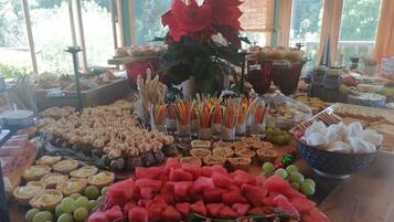 A buffet table with various food items including watermelon, olives, and appetizers.