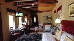 A room with a bed, a desk, and a TV. There is a window with curtains and a lamp on the wall. - Hawklee Country House (Fort Nottingham)