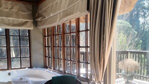 A room with a large window, a wooden table, a chair, and a bathtub. - Hawklee Country House (Fort Nottingham)